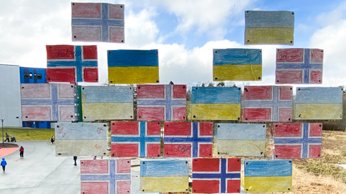 Foto: Arbeids- og inkluderingsdepartementet Tegninger av norske og ukrainske flagg som er hengt opp på et vindu mot en skolegård