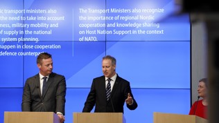 Tre personer ved talerstoler, samferdselsminister Nygård i midten